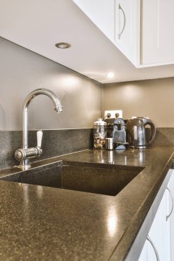 Çağdaş açık mutfak, yemek masası seti ve ferah odada gri kanepe.