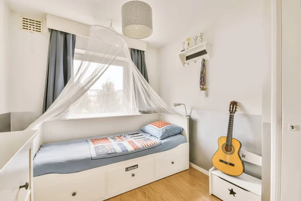 クローゼットの近くにある毛布と枕と小さなベッドルームの窓に対するランプ付きのベッドルームのテーブルと快適なベッドルーム — ストック写真