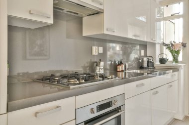 Beyaz duvarları ve fayanslı zemini olan geniş, parlak bir mutfak.