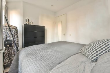 A spacious bright bedroom with a minimalistic black wardrobe and a large panoramic window
