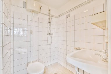 Lavabolu ve duvarlı, beyaz duvarlı ve kareli tuvaletli dar bir tuvalet.