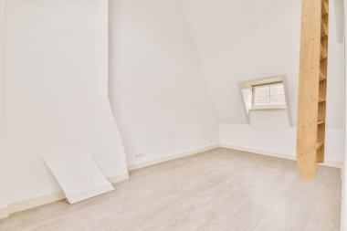 Evdeki boş Mansard ışık odasındaki beyaz duvarda plastik pencere ve radyatör var.