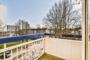 Panoramic view of old brick buildings with parking and trees from small balcony