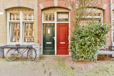 Levhalı, kaldırımlı ve ahşap kapılı bir binanın ön manzarası daireye çıkıyor.