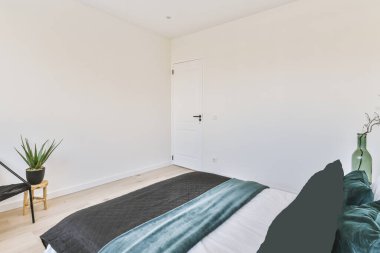 Yastıklı, yorganı olan rahat bir yatak modern bir dairenin parlak yatak odasında bulunur..