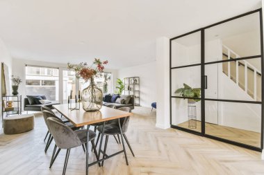 Çağdaş dairenin geniş odasındaki dinlenme odasının yakınındaki sandalyeli ve çiçekli masa