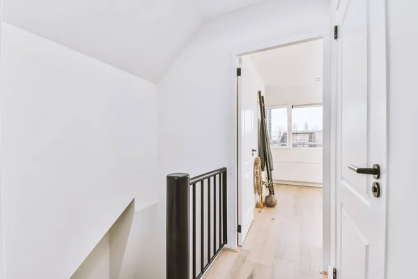 The open white door of a bright attic room, located at the top of the stairs of the house.