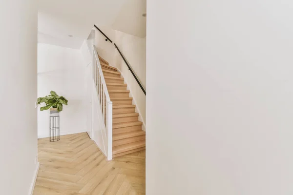 ミニマリストのインテリアデザインのモダンな高級アパートの2階につながる木製の階段付きの白い廊下 — ストック写真