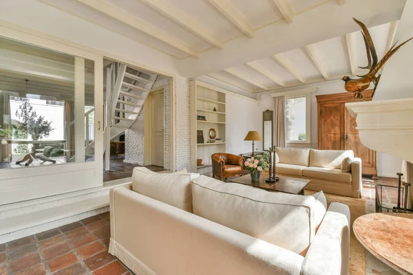 Çağdaş açık mutfak, yemek masası seti ve şömineli gri kanepe.