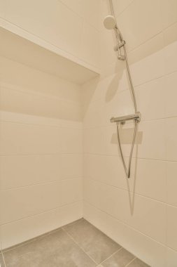 Modern apartmandaki yatak odasının yanında cam duvarlı dar bir banyo.