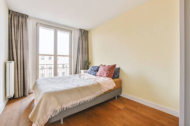 Yatak odasının iç tasarımı, yatak odası ve ahşap gardırop modern dairenin penceresinin kenarına yerleştirilmiş.