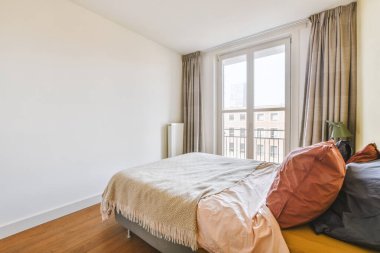 Yatak odasının iç tasarımı, yatak odası ve ahşap gardırop modern dairenin penceresinin kenarına yerleştirilmiş.