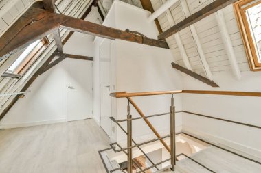 Kapalı beyaz oda kapısı çerçeveli resimlerin yanında ve evdeki merdivenin tepesinde şık bir lamba var.