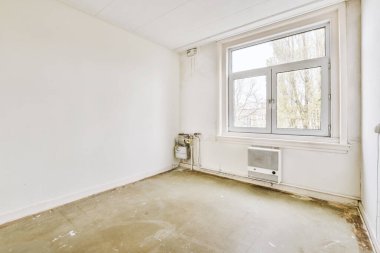 Evdeki boş ışık odasında, beyaz duvardaki plastik pencere ve radyatör.