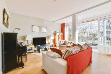 Modern apartmandaki dekorasyonlu ve televizyonlu, rahat koltuğun yanına yerleştirilmiş eski püskü ahşap masa.