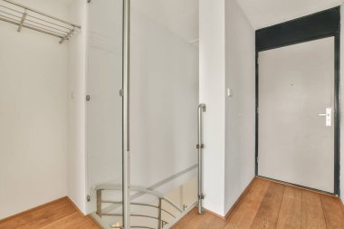 Kapalı beyaz oda kapısı çerçeveli resimlerin yanında ve evdeki merdivenin tepesinde şık bir lamba var.