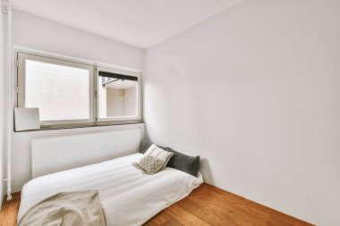 Modern dairenin penceresinin yanında yatağı olan yatak odasının iç tasarımı.