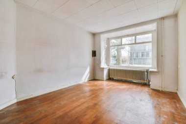 Evdeki boş ışık odasında, beyaz duvardaki plastik pencere ve radyatör.