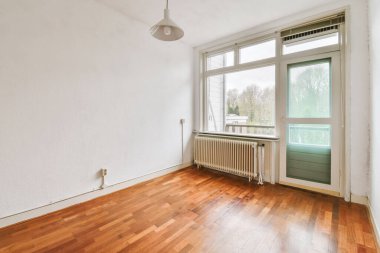 Evdeki boş ışık odasında, beyaz duvardaki plastik pencere ve radyatör.