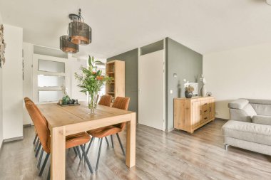 Günümüz minimalist tasarımı. Hafif stüdyo dairesinin ahşap masası ve oturma odası ile beyaz duvarları ve parke zemini arasında yemek masası ve sandalyeleri var.