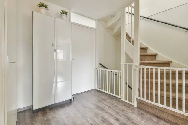 白色螺旋形楼梯将现代房屋的各个楼层与木制地板和白色墙壁连接起来 — 图库照片