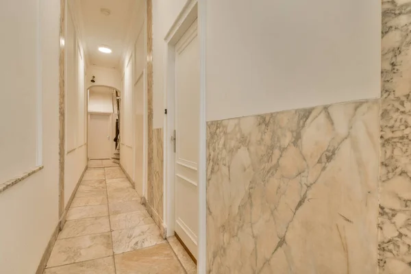 Light narrow hallway with many doors in white walls and glowing lamp over lumber floor