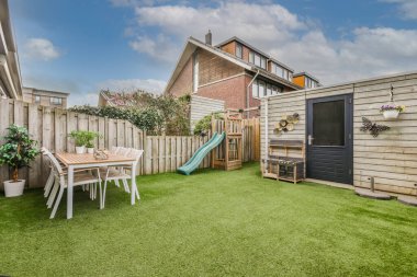 Neat paved patio with sitting area and small garden near wooden fence