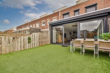 Neat paved patio with sitting area and small garden near wooden fence