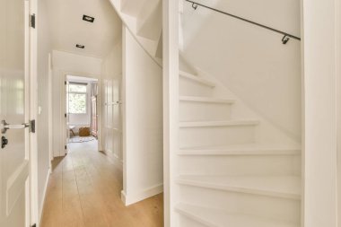 Evin koridorundaki oturma odasına açılan merdiven ve kapının yanındaki dekorasyon ve aynalı retro dolap.