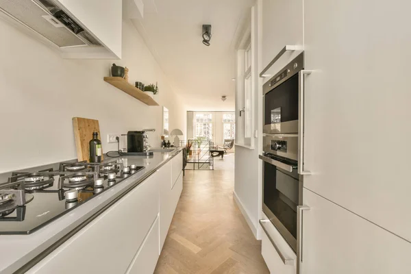 Interior of contemporary kitchen with stylish black cupboards and appliances near dining area in contemporary apartment