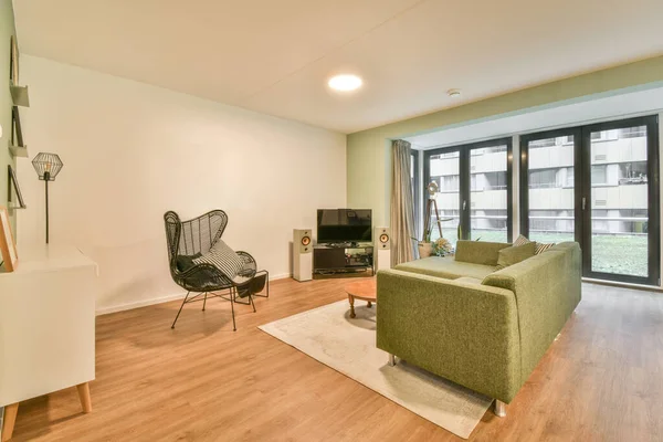 Square table placed on mat near couch and TV in stylish living room of contemporary apartment