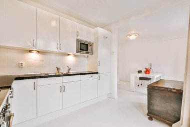 Minimalist tarzı beyaz mobilyalı, lavabolu ve sobalı bir ev mutfağı.