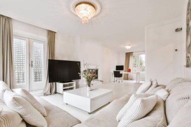 Şık bir oturma odası, rahat bir kanepe ve modern bir dairede masanın etrafına yerleştirilmiş yastıklı koltuklar.