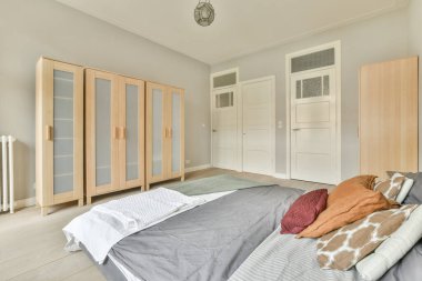 Renkli yastıkları olan rahat bir yatak ve pencerenin yanındaki yeşil duvarlı şık yatak odasında sıcak bir battaniye.