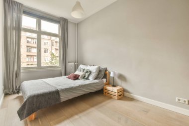 Renkli yastıkları olan rahat bir yatak ve pencerenin yanındaki yeşil duvarlı şık yatak odasında sıcak bir battaniye.