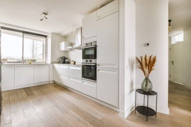 Gündüz vakti modern dolap ve aletlerle aydınlık mutfağın içinde.