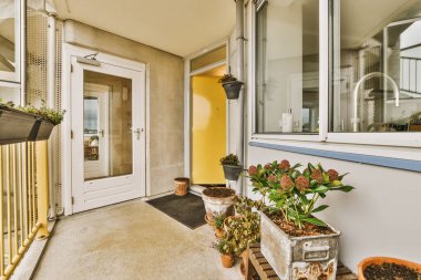 Narrow brick balcony with metal railings, wooden chair and door
