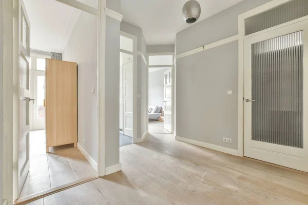 Corridor of contemporary apartment with black closets and opened doorway leading to terrace