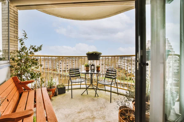 Narrow brick balcony with metal railings, wooden chair and door