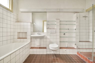Evdeki modern tuvalette asılı duran banyo musluğu ile duvar arasındaki cam bölme.