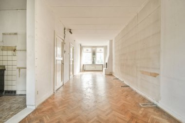 Pencereleri ve ahşap parke zemini olan boş beyaz mutfağın içi.