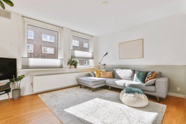 Modern apartmandaki geniş minimalist tarzda oturma odasında halı ve masaya yakın rahat bir kanepe.