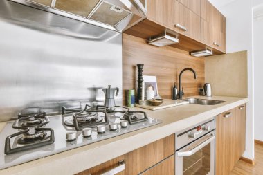 Minimalist stil kahverengi mobilyalı, lavabolu ve sobalı bir ev mutfağı.