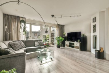 Yastıkları olan rahat bir kanepe. Duvara yaslanmış TV ve dekorasyonlar modern sevgi odasında.