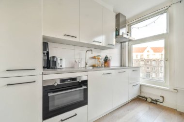 Modern ev mutfağı iç tasarımı beyaz dolaplar, dolaplar ve çelik kapüşon ile çağdaş apartmanda.