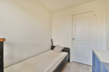 Küçük dar minimalist yatak odasına yerleştirilmiş rahat bir yatak odası. Modern apartmanın beyaz duvarları ve penceresi var.