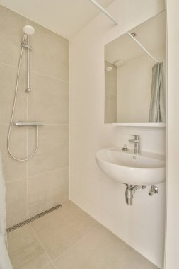 Modern banyoda aynalı lavabo ve cam kapılı duş kutusu ve beyaz fayanslı duvarlar.