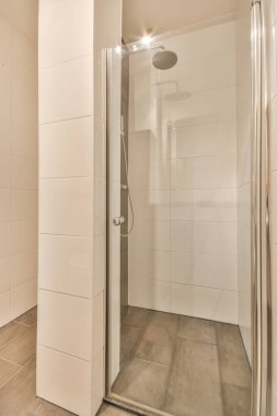 Duş muslukları cam bölmenin yanındaki fayanslı duvara bağlı ve evdeki tuvaletteki süs pervazı.