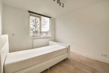 Küçük dar minimalist yatak odasına yerleştirilmiş rahat bir yatak odası. Modern apartmanın beyaz duvarları ve penceresi var.