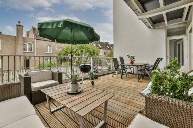 Narrow brick balcony with metal railings, wooden chair and door